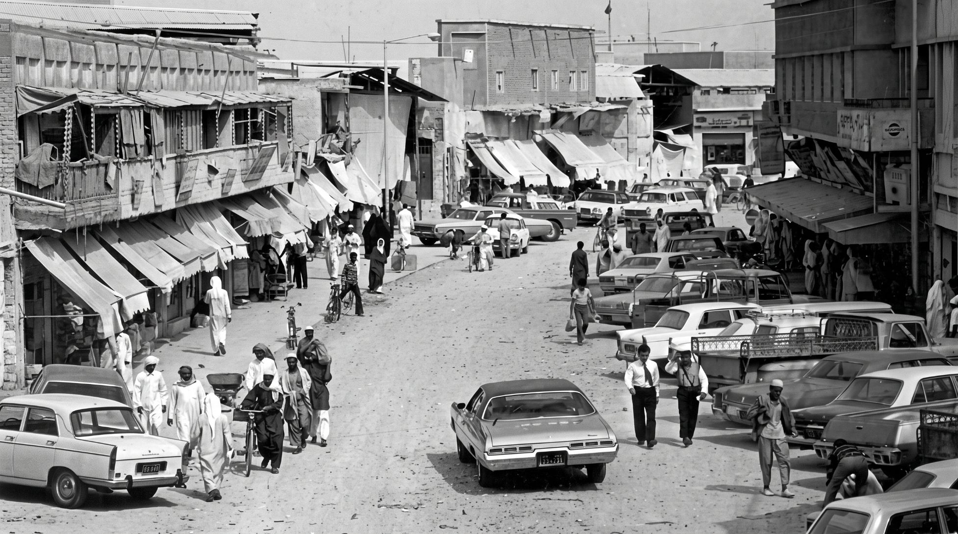 Souq Waqif in the 1970s — a busy street of awnings, shoppers, bicycles and parked cars